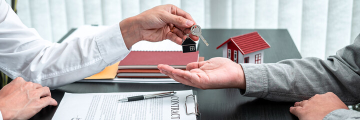 Real estate agent are presenting home loan and giving keys to customer after signing contract to rental house with approved property application insurance form contract