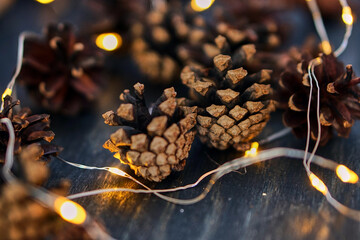 Christmas cones. Yellow garlands. New Year's lights. Holiday image with Christmas golden garland lights and pine cones over wooden background