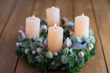 Advent wreath with four burning candles on table