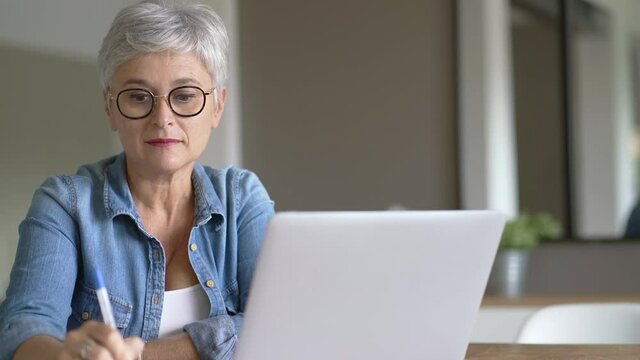 Portrait of a beautiful mature 50-year-old woman with white hair working from home