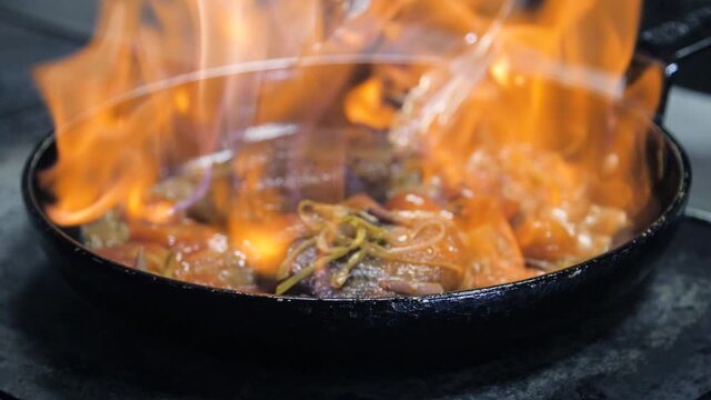 Chef making steak in flambe style on a pan. Oil and Alcohol Ignite with Open Flames. . Food on cuisine. Nutrition in gourmet kitchen. Making meal. Prepare food to eat. Delicious dish