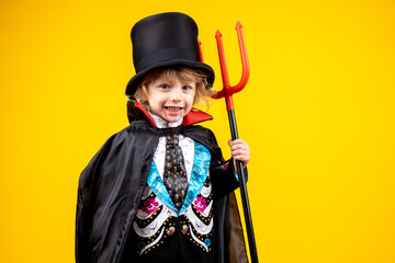 halloween, holiday and childhood concept - boy in dracula costume with black cape and top hat on...
