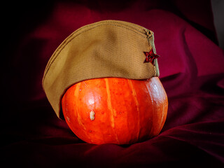 A Soviet Army side cap on a pumpkin on a dark background.
