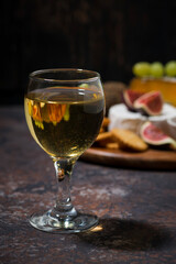glass of white wine and snacks on dark background, vertical