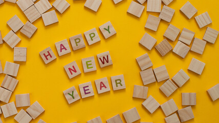 Happy New Year and Merry Christmas. Scrabble letters on yellow background. Letter tiles spelling celebration holiday.