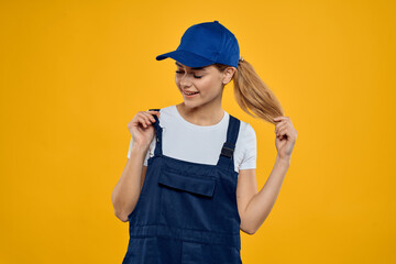 Woman in working uniform blue cap delivering courier service yellow background