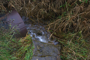 the stream flows into a large metal pipe