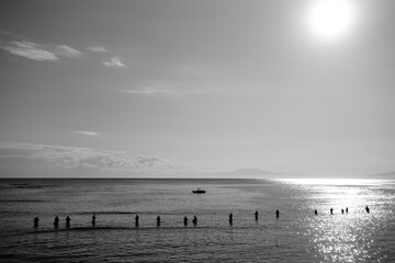 Fototapeta na wymiar 北海道網走市の二ツ岩と、朝日に照らされ海に浸かって釣りをする人々