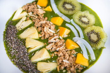 Smoothie bowl with kiwi, coconut, mango, pinapple, granola and chia seeds with green yogurt