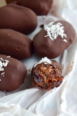 Medjool dates covered dark chocolate filled with almond butter garnish with shredded coconut. Selective focus