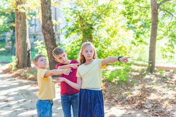 Fototapeta premium Children with a compass point their fingers where to go. Children's rest and entertainment in the park.