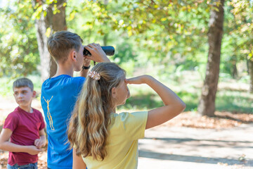 Children on a hike and look through binoculars, children's journey through the forest.