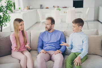 Obraz premium Photo of positive father and two children boy girl talking on weekend sit divan in house living room