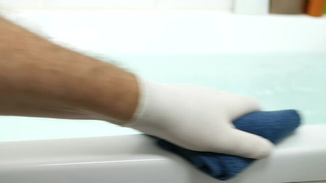 Nurse's Hand Cleaning the Bathtub Surface with a Dry Towel