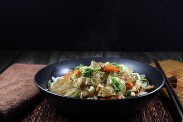 Fried and stirred Korea instant noodle with cutting fresh cabbage, carrot, Chinese celery, corn and tofu on the plate. Famous vegetarian menu in Asia restaurant. High fiber and vitamin food.