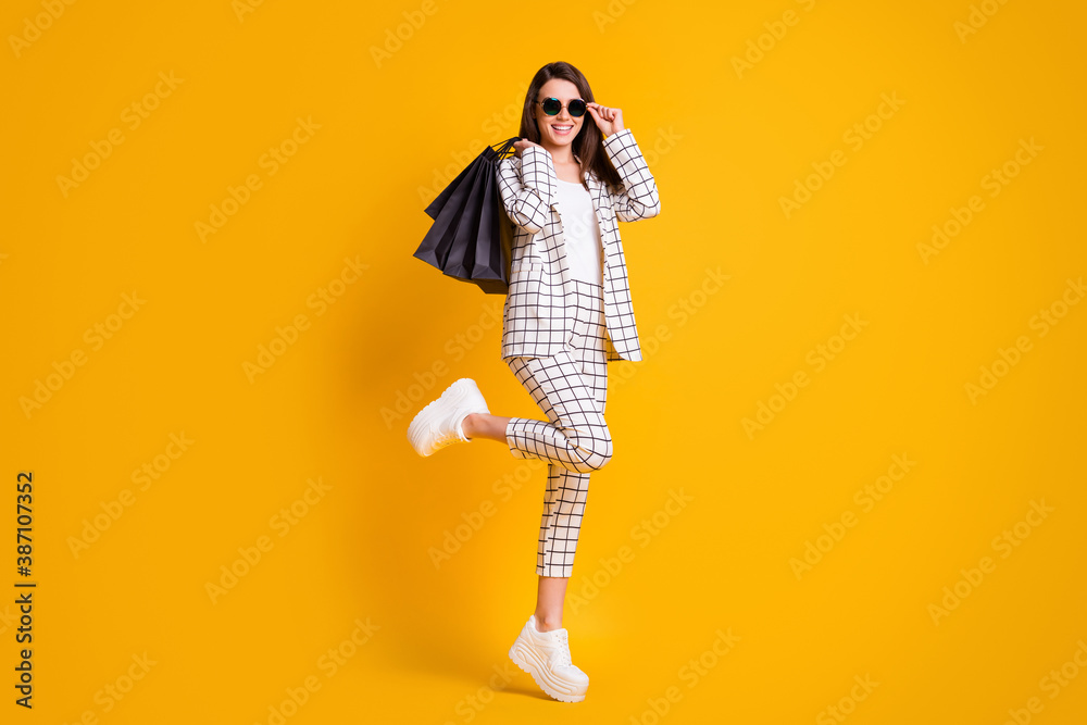 Sticker Full body photo of nice brown hair girl carry boutique bags wear plaid suit white sneakers sunglass isolated yellow color background