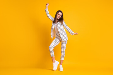 Fototapeta na wymiar Full length body size photo of dancing girl wearing white checkered formal wear smiling isolated on bright yellow color background