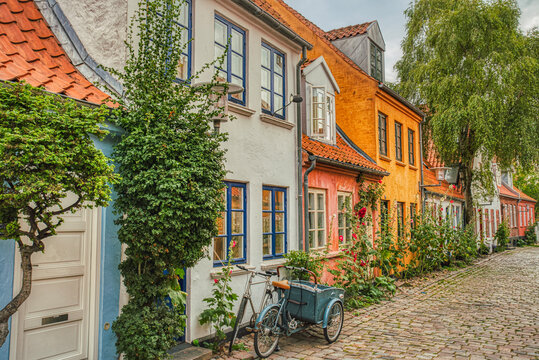 A traditional Scandinavian Cargo bicycle (Christiania Bike) parked at a house entrance in a cozy downtown street by a colorful facade. Danish lifestyle and culture illustration - Aarhus, Denmark