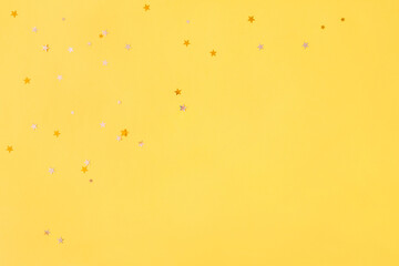 Photo of Christmas background with glitter stars on yellow paper with copy space. Celebration, party concept