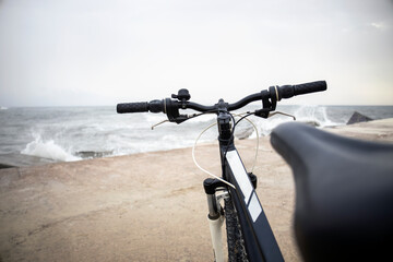 Fototapeta na wymiar Close-up Of Bicycle Handlebar on the beach on rainy day with waves