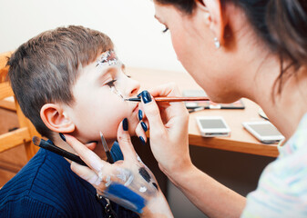 little cute child making facepaint on birthday party, zombie Apocalypse facepainting, halloween preparing concept, lifestyle people