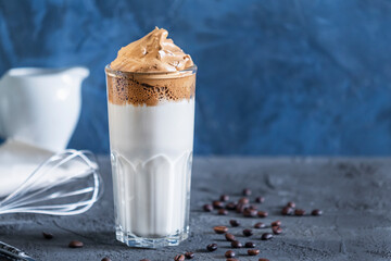 On a blue background dalgon coffee close-up. Delicious popular drink. Photo with place for text.