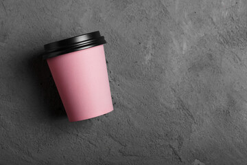 Pink paper cup of coffee to go or tea om grey concrete background. Mock-up for branding. 