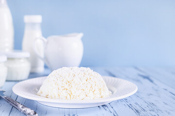 Fresh homemade cottage cheese close-up. Set of dairy products on a blue background. Photo with copy space.