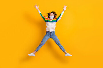 Fototapeta na wymiar Full size photo of crazy lady jump like star rejoicing wear medical mask sweater jeans footwear isolated on yellow background