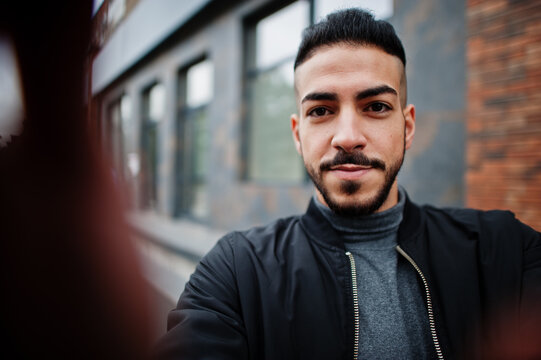 Portrait of stylish arab beard man wear grey turtleneck and black jaket. Arabian model guy make selfie by camera.