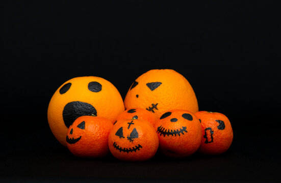 oranges and mandarins painted like a halloween pumpkin, happy halloween citrus