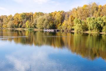 view of calm pond in city park on sunny autumn day