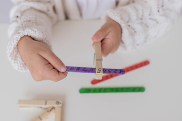 The child using craft sticks for learning numbers, early childhood. clothespin and coloraturas sticks are easy diy for motor skills, eye-hand coordination, and concentration.