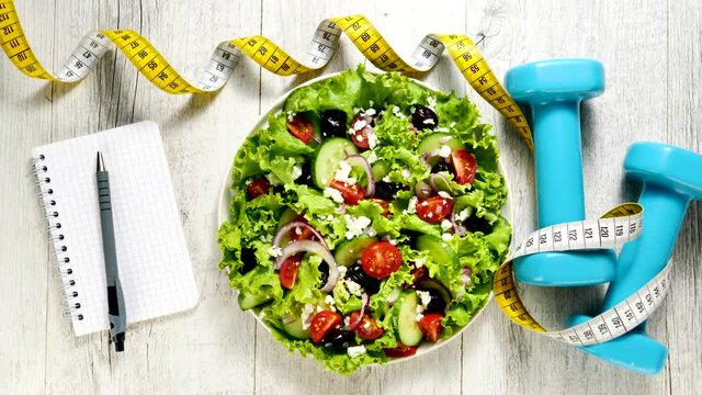 diet food concept- vegetable salad with meter and dumbbell