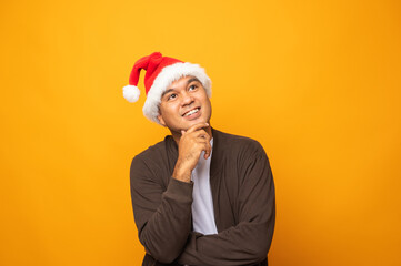 Young handsome asian man wearing christmas hat and thinking look