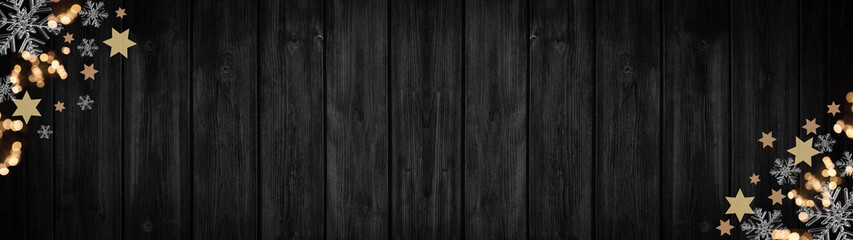Fototapeta premium Festive decorative Christmas / Advent background banner panorama template - Bokeh lights, stars and ice crystals, isolated on dark black rustic wooden boards wall texture, with space for text