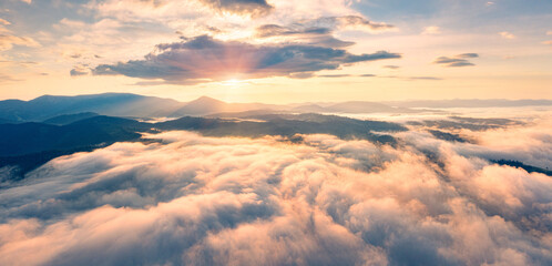 Flying above the clouds on drone. Panoramic morning view of Carpathian mountains with Homiak...