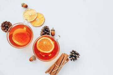 Cozy autumn flat lay composition with copy space. Cup of tea, lemon, cinnamon, and cones on a white background