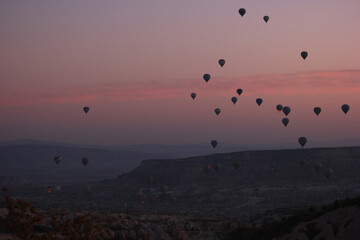Hot air balloons flying over rocky landscape at sunset sky. Goreme, Cappadocia, Turkey.