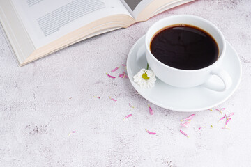 Cup of white coffee with a book and flowers on gray stone background. Space for text. Selective focus. Relax time. Concept of relax time