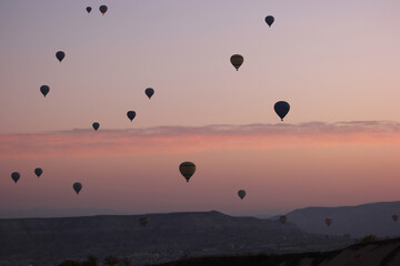 Red sunset sky with flying hot air balloons. Silhouettes of hot air balloons over sunset background. Concept of aerial adventure.