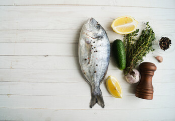 Raw fish cooking and ingredients. Dorado, lemon, herbs and spices. Top view on stone table