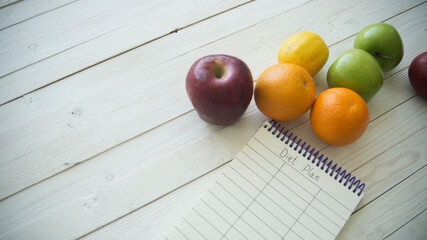 Full paper bag of food products with blank little notebook on wooden table, top view