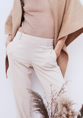 Stylish Pants and sweater. Details of everyday look. Model wearing casual beige outfit. Trendy minimalistic style. Beige aesthetics. Fashion look book. Warm Fall Winter seasons