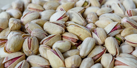 Background make from salt pistachios (into nutshells). Close up. Whole background. Panorama.