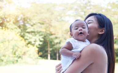 Fototapeta premium Picture of happy mother with baby in garden. Portrait of beautiful young asian mother holding her newborn baby.