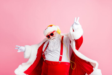 Photo modern funky santa claus listen x-mas christmas stereo radio use headphones raise hands fingers wear style stylish big belly costume pants headwear isolated pastel color background