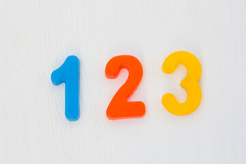 Colorful plastic numeral one, two, three on white background. Learning numbers and counting with fridge magnets