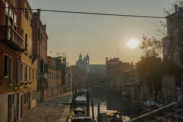 Venice, Italy - 24/01/18
Walm sunset and cozy atmopheric cityscape.
Gondola and boat at the port near the houses.