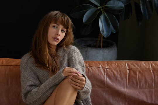 Young woman in a sweater sitting on a sofa